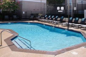 Sonesta ES Suites Dallas Medical Market Center’s outdoor pool has sun loungers as well as armchairs and coffee tables by its side.