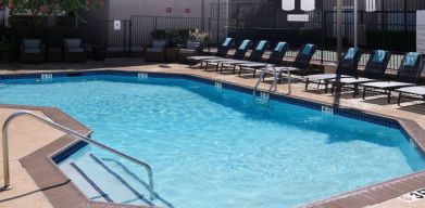 Sonesta ES Suites Dallas Medical Market Center’s outdoor pool has sun loungers as well as armchairs and coffee tables by its side.