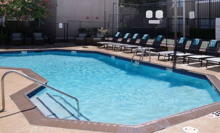 Sonesta ES Suites Dallas Medical Market Center’s outdoor pool has sun loungers as well as armchairs and coffee tables by its side.