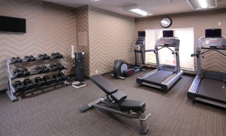 Sonesta ES Suites Dallas Medical Market Center’s fitness center has an assortment of exercise equipment including free weights, and a wall-mounted television.