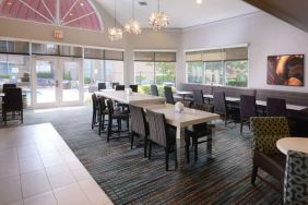 Sonesta ES Suites Dallas Medical Market Center’s lobby is furnished with a mix of table sizes and both regular and tall chairs, with plenty of natural light flowing through large windows.