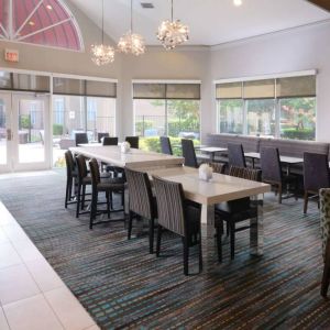 Sonesta ES Suites Dallas Medical Market Center’s lobby is furnished with a mix of table sizes and both regular and tall chairs, with plenty of natural light flowing through large windows.