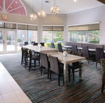 Sonesta ES Suites Dallas Medical Market Center’s lobby is furnished with a mix of table sizes and both regular and tall chairs, with plenty of natural light flowing through large windows.