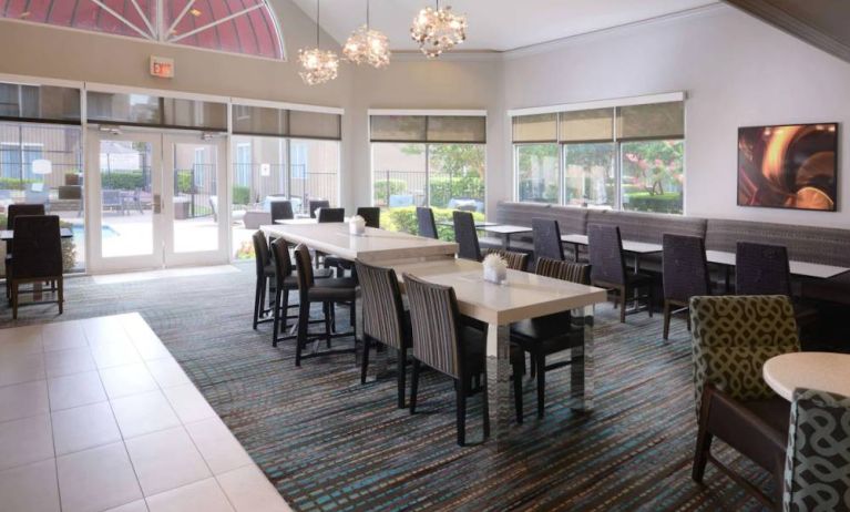 Sonesta ES Suites Dallas Medical Market Center’s lobby is furnished with a mix of table sizes and both regular and tall chairs, with plenty of natural light flowing through large windows.