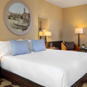 Royal Sonesta Chicago River North double bed guest room, furnished with bedside lamps, coffee table, and an armchair.