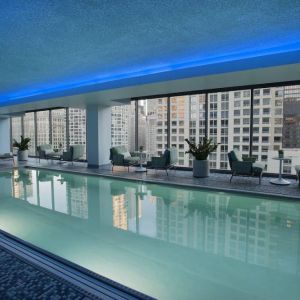 Royal Sonesta Chicago River North’s indoor pool features floor-to-ceiling windows and tables and chairs, and loungers, by the side.