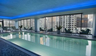 Royal Sonesta Chicago River North’s indoor pool features floor-to-ceiling windows and tables and chairs, and loungers, by the side.