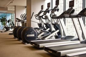 The hotel fitness center is equipped with a range of exercise machines, and large windows with city views.