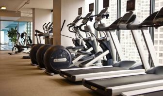 The hotel fitness center is equipped with a range of exercise machines, and large windows with city views.