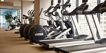 The hotel fitness center is equipped with a range of exercise machines, and large windows with city views.