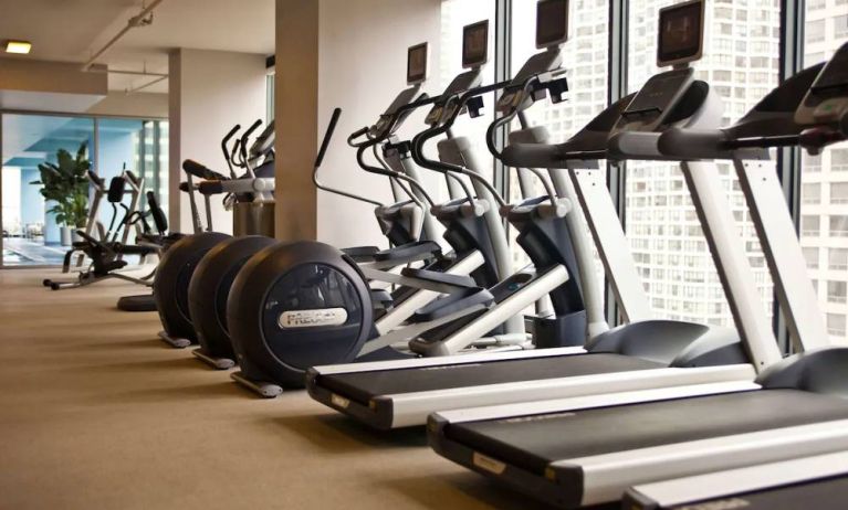 The hotel fitness center is equipped with a range of exercise machines, and large windows with city views.