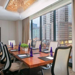 Hotel meeting room, with long wooden table, eight swivel chairs, and floor-to-ceiling windows.