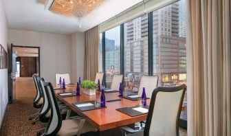 Hotel meeting room, with long wooden table, eight swivel chairs, and floor-to-ceiling windows.