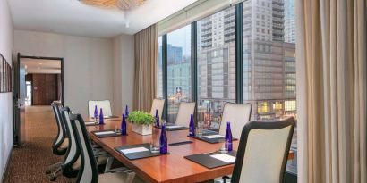 Hotel meeting room, with long wooden table, eight swivel chairs, and floor-to-ceiling windows.