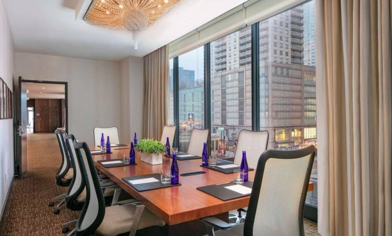 Hotel meeting room, with long wooden table, eight swivel chairs, and floor-to-ceiling windows.