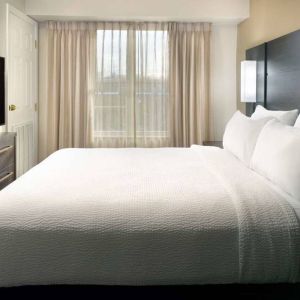 Double bed guest room with a window and large TV at Sonesta ES Suites Raleigh Durham Airport Morrisville.