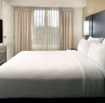 Double bed guest room with a window and large TV at Sonesta ES Suites Raleigh Durham Airport Morrisville.