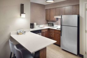 Guest room kitchen in Sonesta ES Suites Raleigh Durham Airport Morrisville, featuring fridge-freezer, hob, microwave, and table.