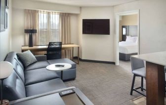 Double bed guest room living area in Sonesta ES Suites Raleigh Durham Airport Morrisville, with sofa, window, and TV.