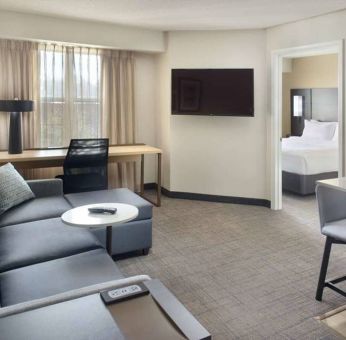 Double bed guest room living area in Sonesta ES Suites Raleigh Durham Airport Morrisville, with sofa, window, and TV.