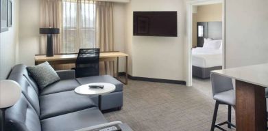 Double bed guest room living area in Sonesta ES Suites Raleigh Durham Airport Morrisville, with sofa, window, and TV.