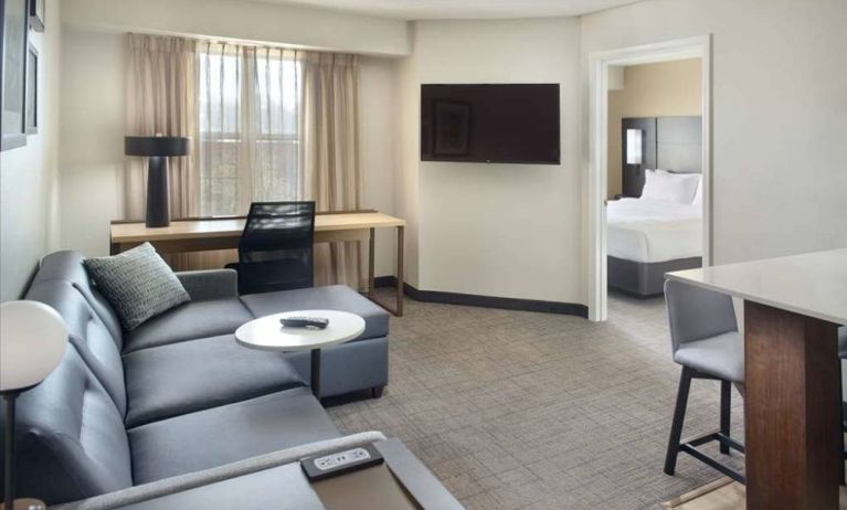 Double bed guest room living area in Sonesta ES Suites Raleigh Durham Airport Morrisville, with sofa, window, and TV.