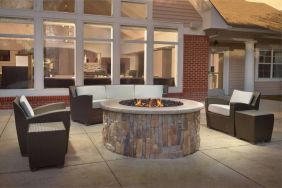 Fire pit surrounded by armchair and sofa seating, plus coffee tables, at Sonesta ES Suites Raleigh Durham Airport Morrisville.