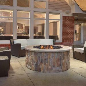 Fire pit surrounded by armchair and sofa seating, plus coffee tables, at Sonesta ES Suites Raleigh Durham Airport Morrisville.