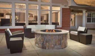 Fire pit surrounded by armchair and sofa seating, plus coffee tables, at Sonesta ES Suites Raleigh Durham Airport Morrisville.