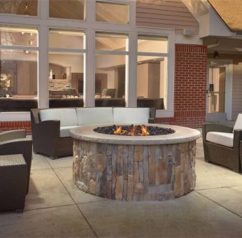 Fire pit surrounded by armchair and sofa seating, plus coffee tables, at Sonesta ES Suites Raleigh Durham Airport Morrisville.