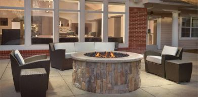 Fire pit surrounded by armchair and sofa seating, plus coffee tables, at Sonesta ES Suites Raleigh Durham Airport Morrisville.