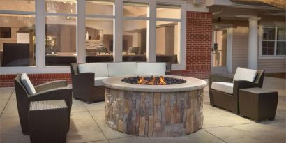 Fire pit surrounded by armchair and sofa seating, plus coffee tables, at Sonesta ES Suites Raleigh Durham Airport Morrisville.