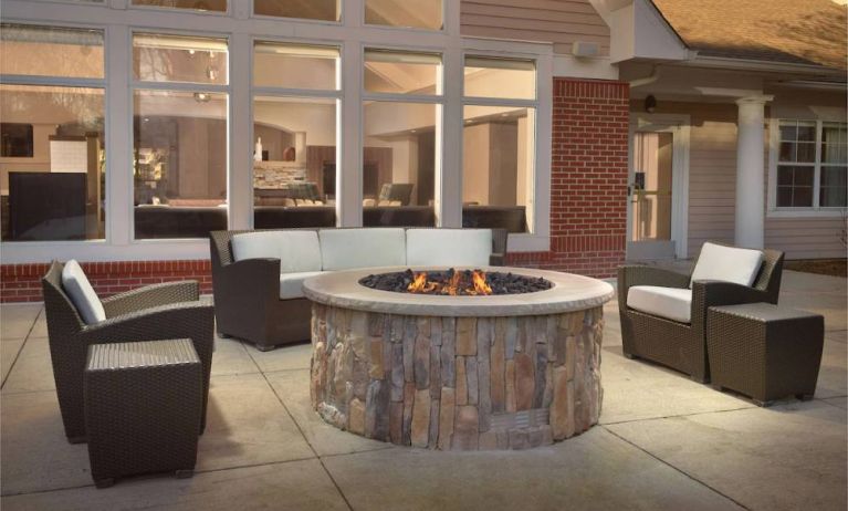 Fire pit surrounded by armchair and sofa seating, plus coffee tables, at Sonesta ES Suites Raleigh Durham Airport Morrisville.