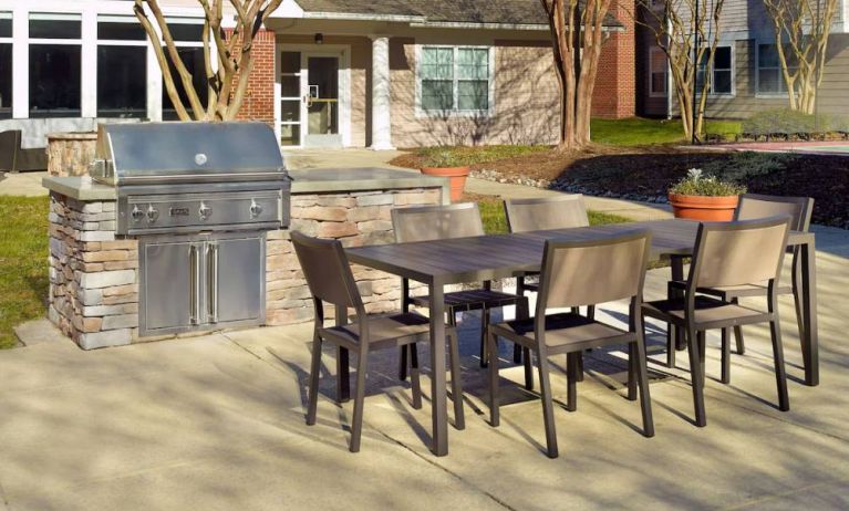 Barbecue with table and six chairs nearby at Sonesta ES Suites Raleigh Durham Airport Morrisville.