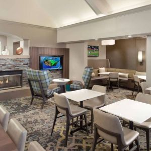 Lobby lounge furnished with sofa seating, tables and chairs, a fireplace and TV, at Sonesta ES Suites Raleigh Durham Airport Morrisville.