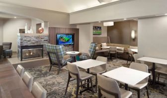 Lobby lounge furnished with sofa seating, tables and chairs, a fireplace and TV, at Sonesta ES Suites Raleigh Durham Airport Morrisville.