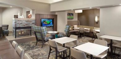 Lobby lounge furnished with sofa seating, tables and chairs, a fireplace and TV, at Sonesta ES Suites Raleigh Durham Airport Morrisville.