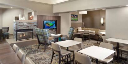 Lobby lounge furnished with sofa seating, tables and chairs, a fireplace and TV, at Sonesta ES Suites Raleigh Durham Airport Morrisville.