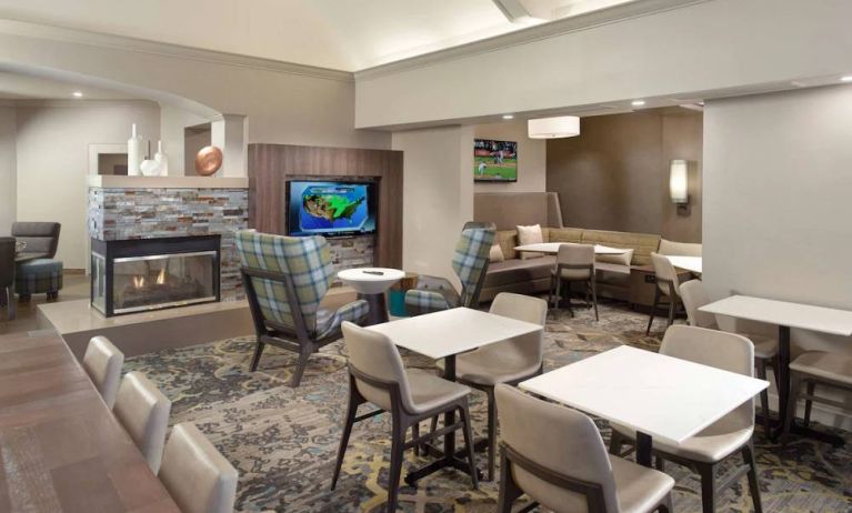 Lobby lounge furnished with sofa seating, tables and chairs, a fireplace and TV, at Sonesta ES Suites Raleigh Durham Airport Morrisville.