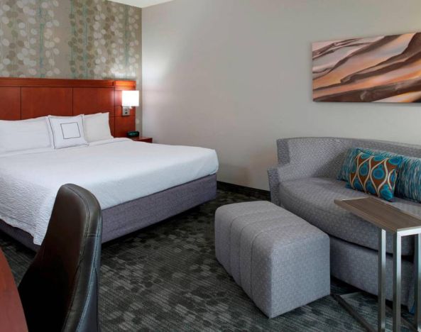 Sonesta Select Kansas City Airport Tiffany Springs double bed guest room furnished with art on the wall and a sofa.