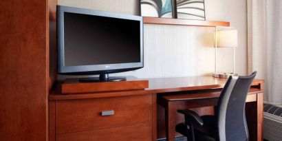 Guest room workspace desk, chair, lamp, and TV at Sonesta Select Kansas City Airport Tiffany Springs.