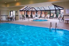 Indoor pool with nearby hot tub and lift, large windows and many chairs, at Sonesta Select Kansas City Airport Tiffany Springs.