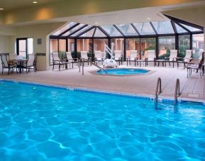 Indoor pool with nearby hot tub and lift, large windows and many chairs, at Sonesta Select Kansas City Airport Tiffany Springs.