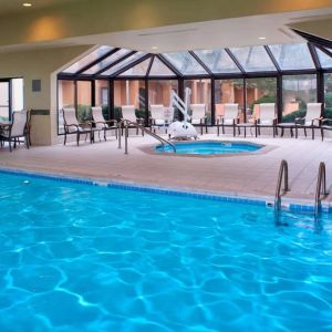 Indoor pool with nearby hot tub and lift, large windows and many chairs, at Sonesta Select Kansas City Airport Tiffany Springs.