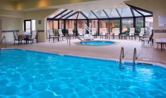 Indoor pool with nearby hot tub and lift, large windows and many chairs, at Sonesta Select Kansas City Airport Tiffany Springs.