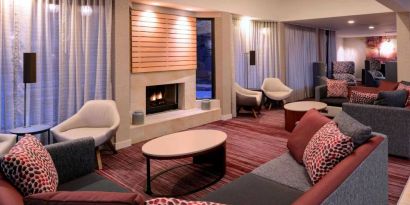 Sonesta Select Kansas City Airport Tiffany Springs’ lobby lounge is furnished with comfy chairs and sofa seating, and a fireplace.