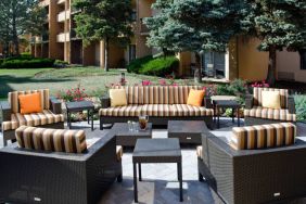 Patio area with sofa and armchair seating alongside coffee tables and pleasant greenery at Sonesta Select Kansas City Airport Tiffany Springs.