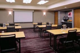 Hotel meeting room, with tables arranged in a classroom format facing a projector screen.