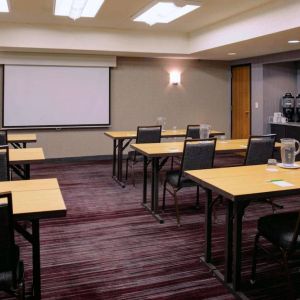 Hotel meeting room, with tables arranged in a classroom format facing a projector screen.