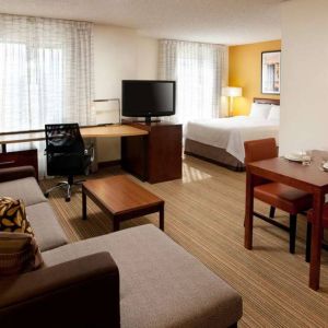 Sonesta ES Suites San Antonio Downtown Alamo Plaza double bed guest room living area, featuring table and chairs, sofa, windows, and a TV.